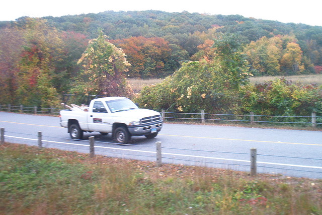 train view of the fall trees and some unknown truck